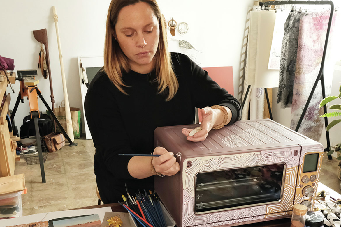 Lucy Simpson, Indigenous artist, paints a microwave in a workshop (Indigenous artists)