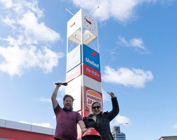 Fifi Box and Nick Cody from Fox FM stand in front of the pillar with the Kingsway clock about to press a giant red go-button. Both are pointing up at the clock. (Pie Face)