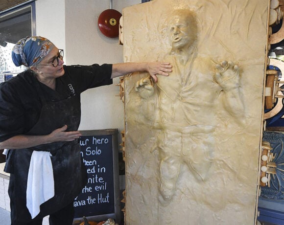 A woman stands in front of a bakery next to a giant 6-ft tall sculpture of Han Solo trapped in carbonite made out of bread (Pan Solo)