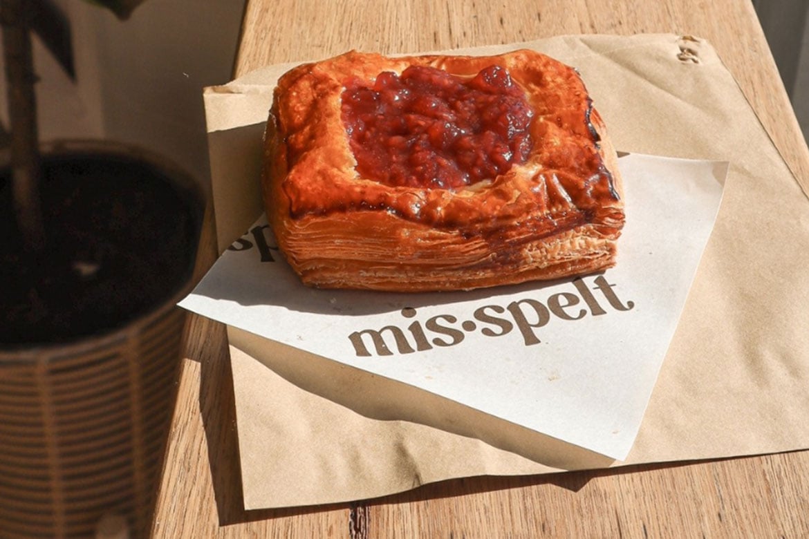 A square Danish filled with berry jam rests on a napkin with the words 