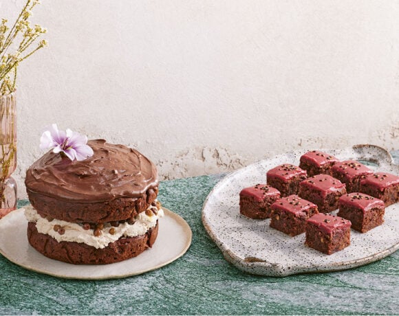 A delicious looking beetroot, chocolate, and wattleseed cake sits next to a plate full of mini-cakes