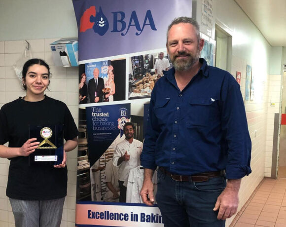 Olivia Baugh holding her trophy standing next to boss Jason Marion in front of a BAA sign (Excellence in Baking)