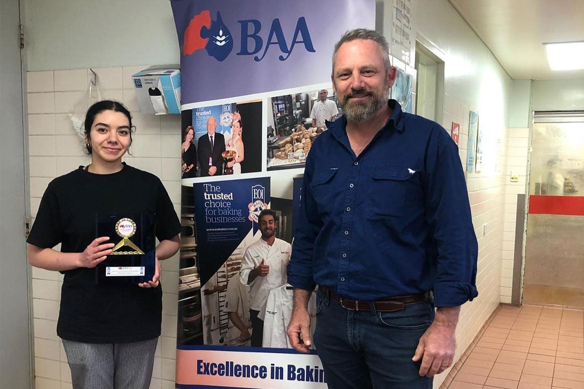 Olivia Baugh holding her trophy standing next to boss Jason Marion in front of a BAA sign (Excellence in Baking)