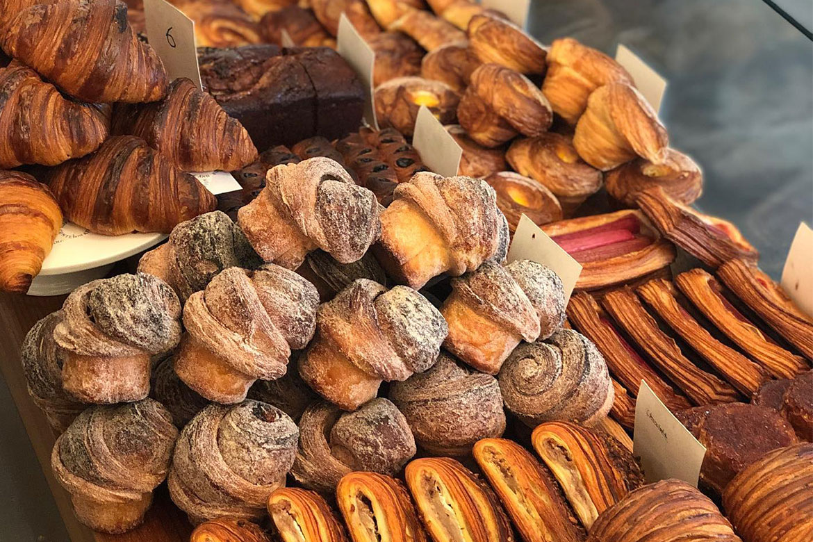 A selection of different viennoiseries on a table (All Are Welcome)