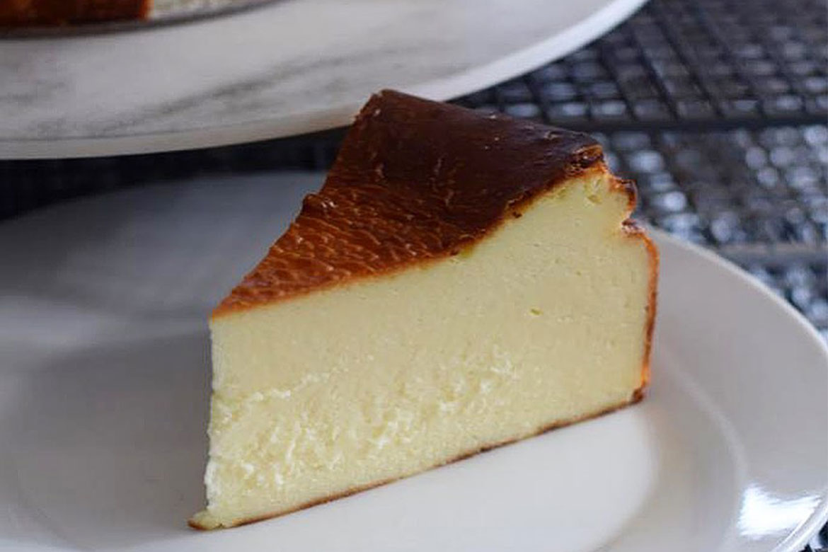 A slice of baked cheesecake sits on a plate (Butter Crumbs)