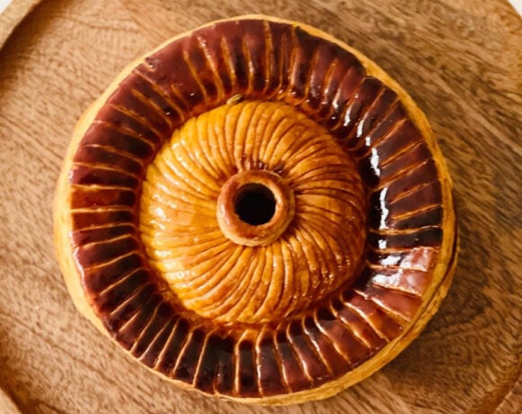A pithivier sits on a wooden board, image shot from above (LoDe Pies)