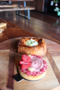 A Danish and a pastry sitting on a wooden board on a table (Doughcraft)