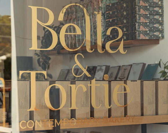 A glass wall with 'Bella & Tortie' written on it in gold lettering