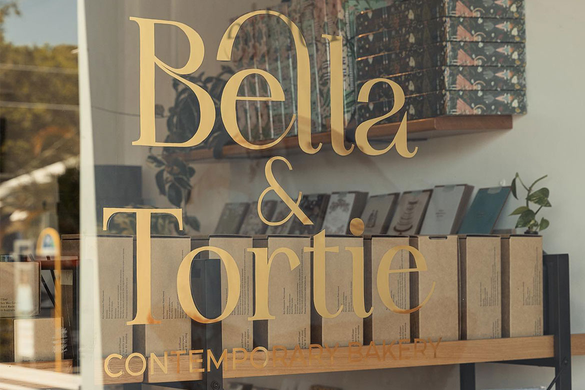 A glass wall with 'Bella & Tortie' written on it in gold lettering