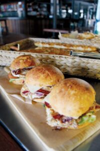 Three sandwiches sitting on a wooden cutting board (Doughcraft)