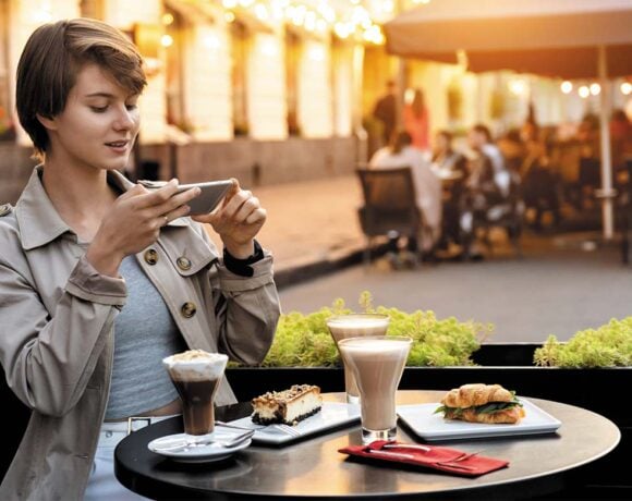 A woman takes a picture of her food at a cafe (influencer culture)