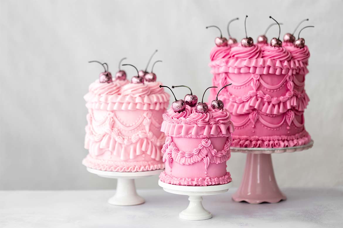 Three beautifully piped pink cakes topped with cherries (piping)