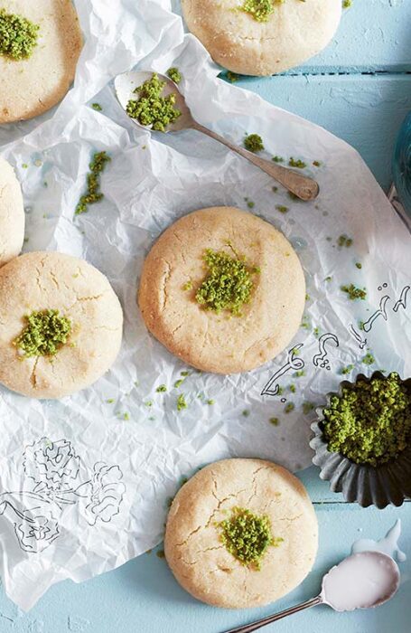 Khetayee khetayee biscuits sitting on a decorative doily next to a blue kettle