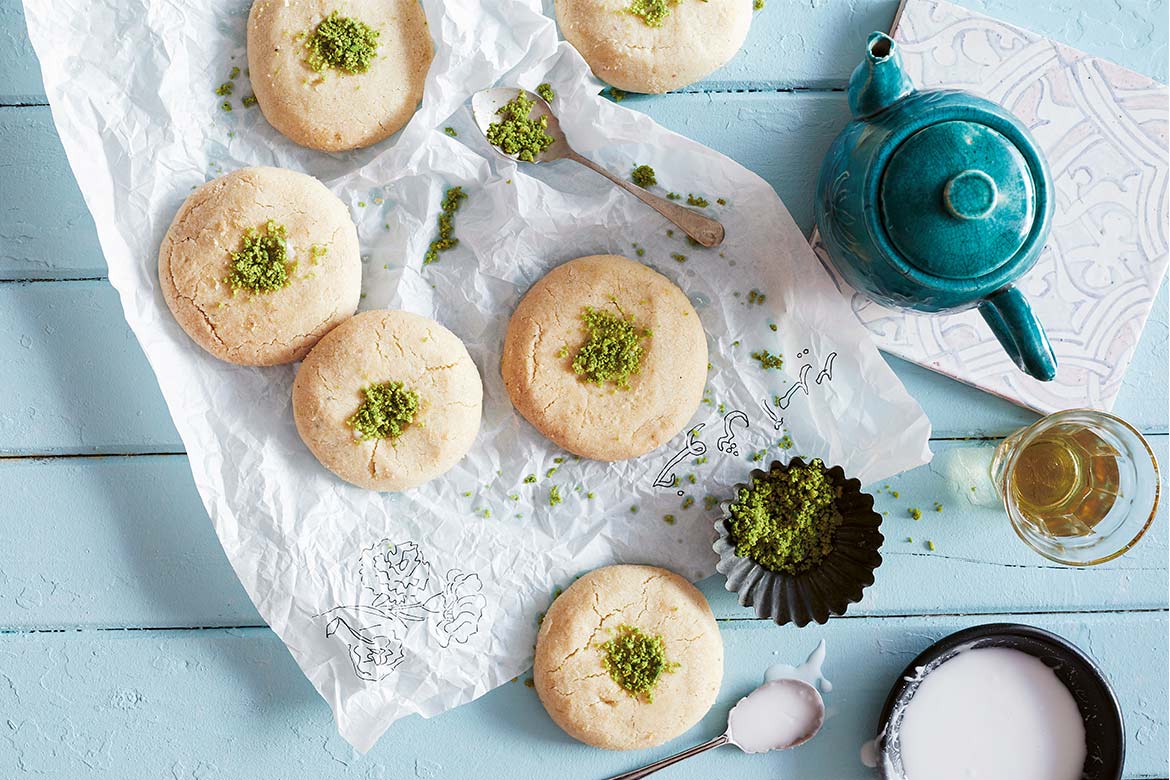 khetayee biscuits sitting on a decorative doily next to a blue kettle