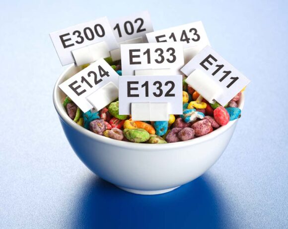 a bowl full of popcorn with lots of signs with the names of artificial colours on them (Harris Farm)
