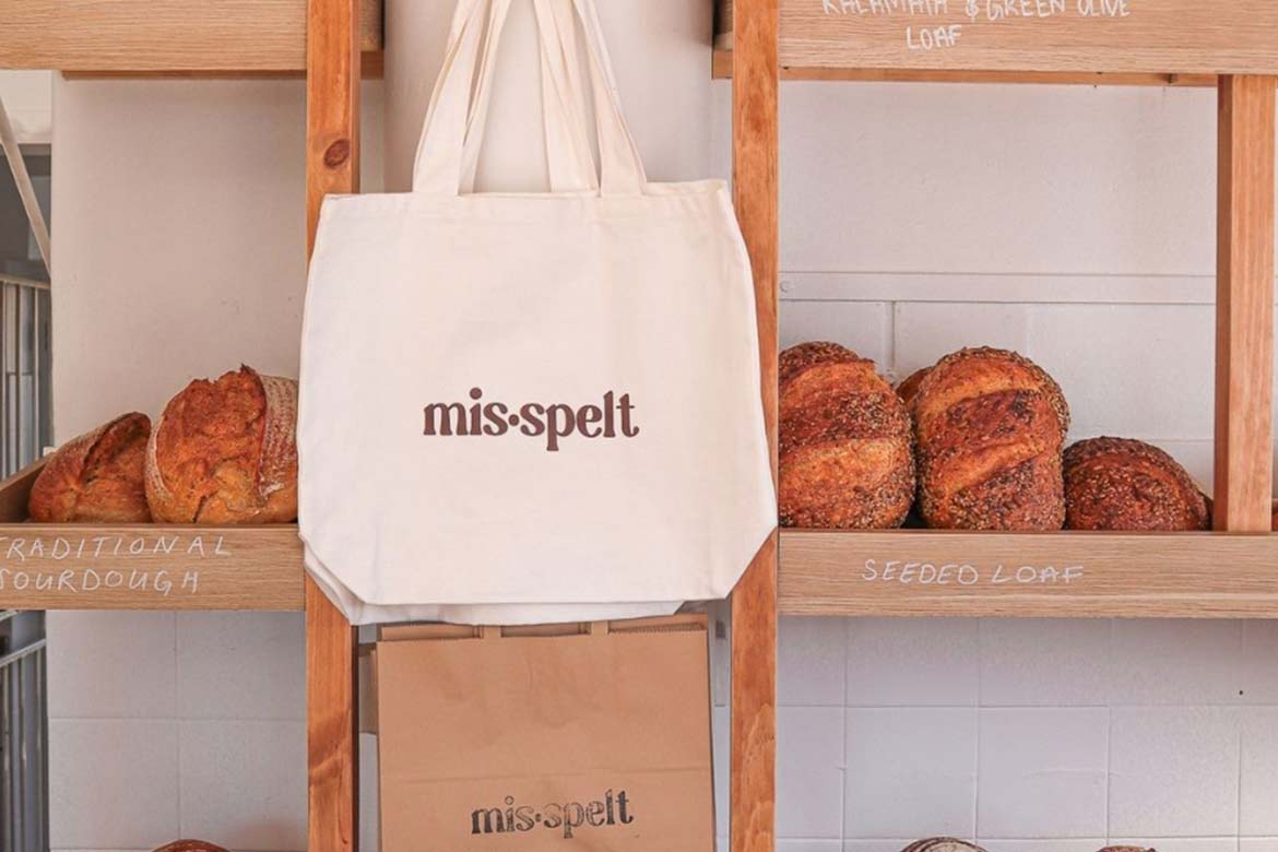 A bag hands on a wooden shelf full of bread (Mis•spelt)