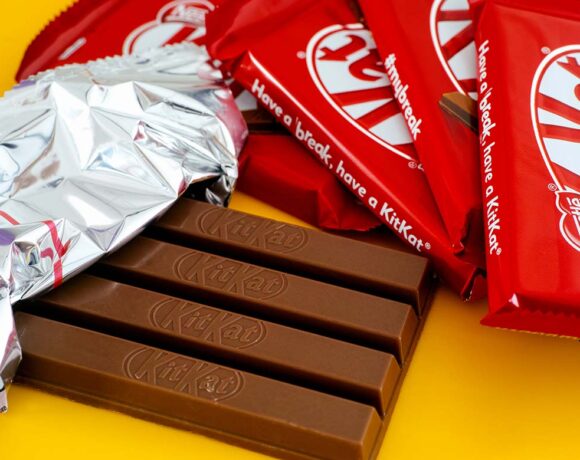 One open KitKat chocolate bar surrounded by other kitkat bars on a yellow background. (paperization)