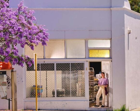 Natasha Brownfield stands in the doorway of Teeter Bakery holding a baking tray