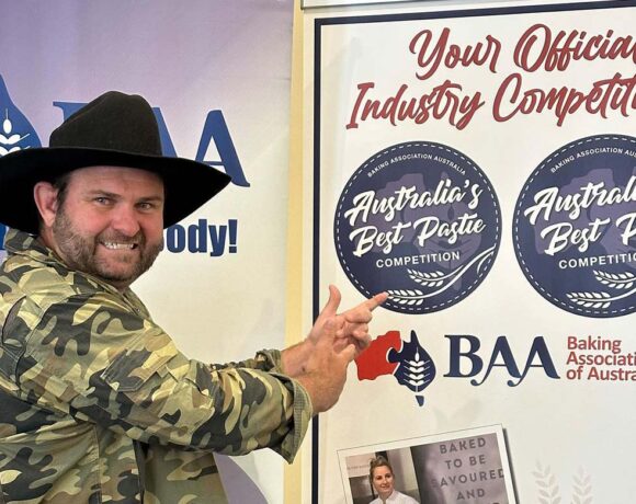 Shaun Pyne stands next to a sign for the Baking Industry Trade Show