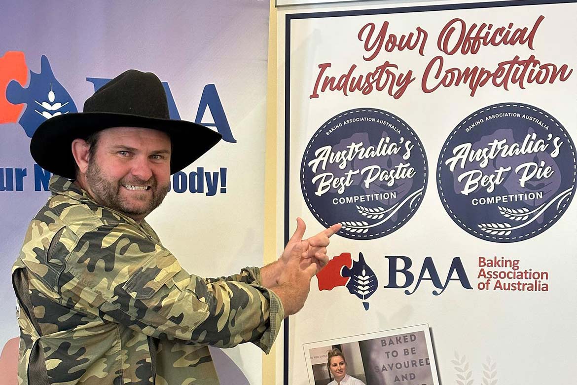 Shaun Pyne stands next to a sign for the Baking Industry Trade Show