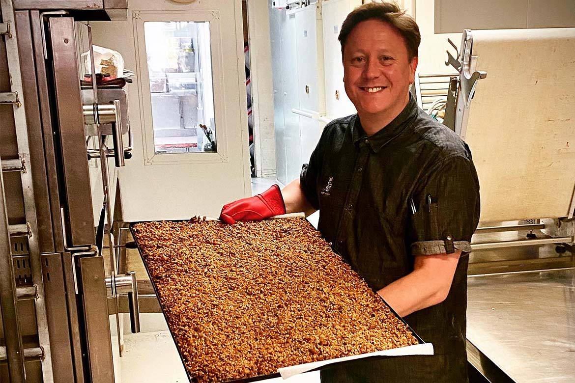 Darren Purchese hold a sheet pan full of granola (Burch & Purchese)