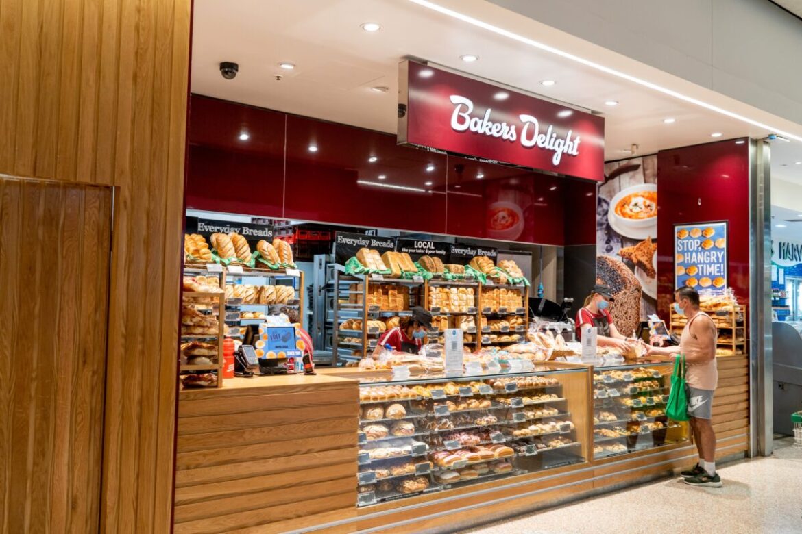 Exterior view of Bakers Delight bakery - a part of large Australian-owned bakery franchise chain with over 700 local outlets. Customer buying bread at local bakery.