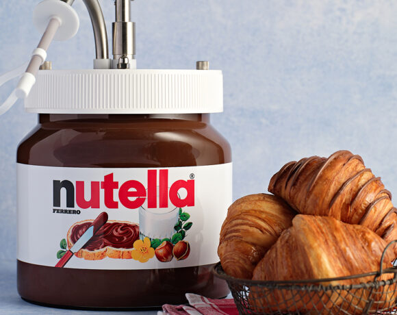 Nutella dispenser sitting next to a small metal basket full of croissants