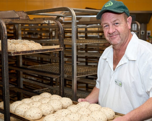 Nicol Strang holding a tray of unbaked bread rolls in the Woolworths kitchen