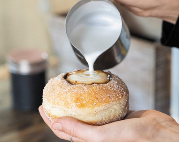 Someone pouring frothed milk into a doughnut with the middle carved out (like a cup) (Kenilworth)