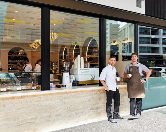 Adrien Marcinowski and Maxime Bournazel stand at the counter of Rise Bakery holding coffees