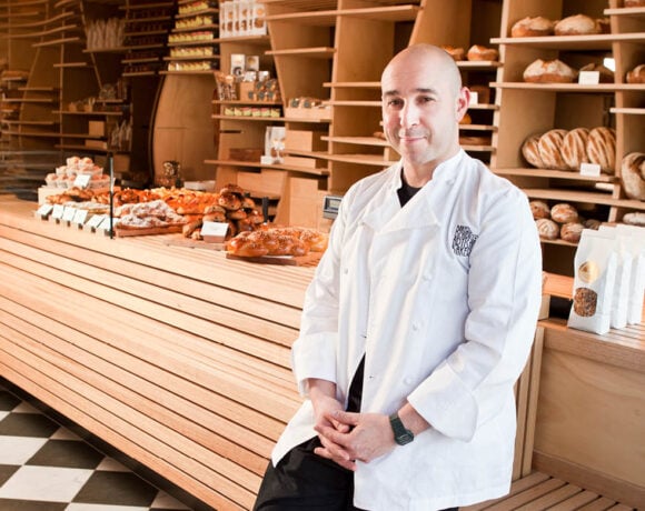 Daniel Chirico leans against the counter at Baker D Chirico. He's smiling at the camera.