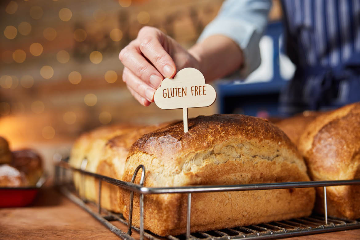 Specialty bakery products such as gluten-free bread are expected to rise in popularity. Pictured is a loaf of sourdough with a gluten-free sign being put in the top by a sales assistant