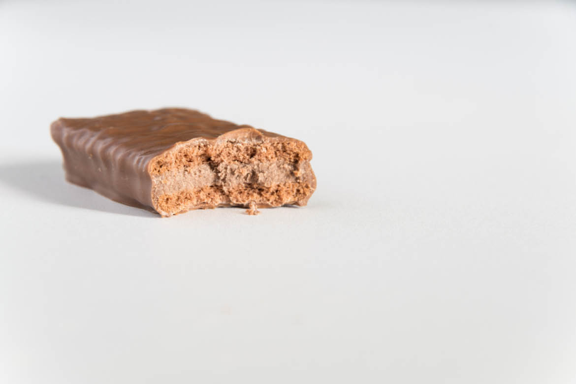 A Tim Tam biscuit rests on a white background. A bite has been taken out of the side facing the camera.