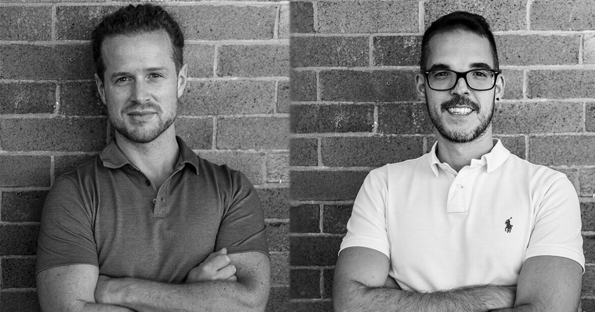 Matteo and Guiseppe standing against a brick wall with their arms crossed