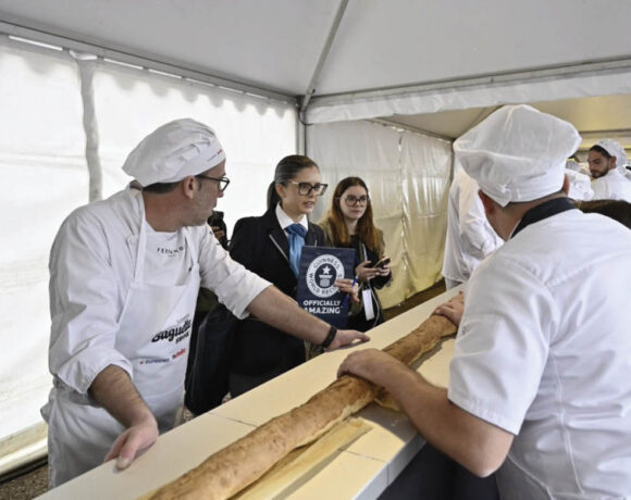 A new baguette world record has been set. Pictured is two bakers with their hands on a section of the baguette. Bearby is a schoolgirl in a blue blazer holding the Guinness World Record certificate.