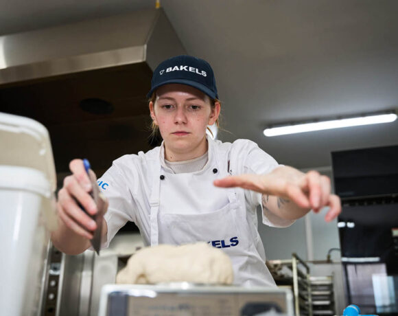 LA Judge winner Imogen Fearon is reaching towards the camera across the kitchen bench. She's reaching for dough and has a look of concentration on her face.