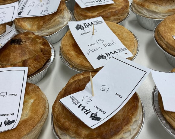 Pie entries for the Queensland Baking Show. Pictured is a close up of pies on a white table. Each pie has a white piece of paper on the top with the BAA and type of pie written on it.