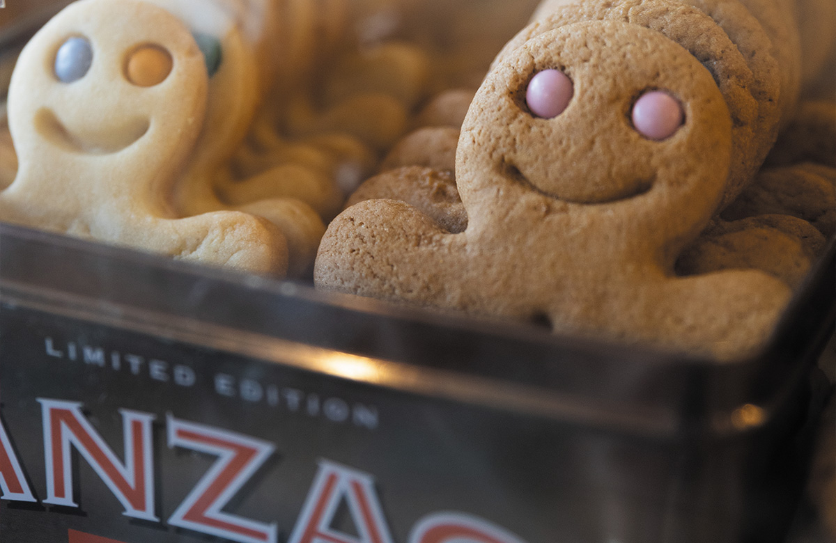 Gingerbread men sit onside an Anzac biscuit tin