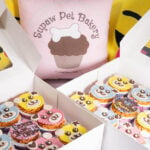 Supaw Pet Bakery's products are in white boxes. In each box is an array of white, yellow and blue if cupcakes. Each cupcake is decorated with chocolate eyes and mouth to resemble a dog.