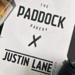 Paddock Bakery is hosting a pop-up shop in Fortitude Valley. Pictured is a sign that says Paddock x Justin Lane in black text on a white sheet of paper.