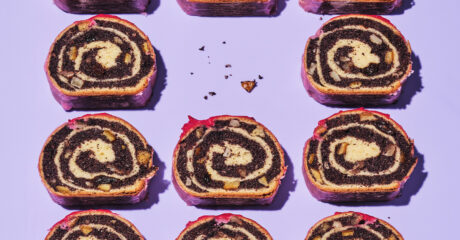 Polish poppy seed roulade sit on a purple background. The roulade has been cut to show the interior roll