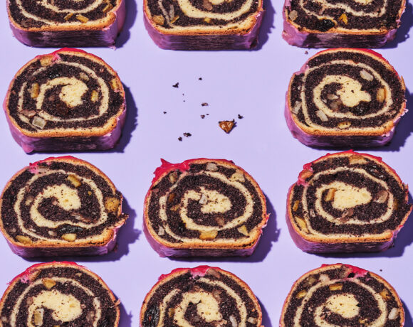 Polish poppy seed roulade sit on a purple background. The roulade has been cut to show the interior roll