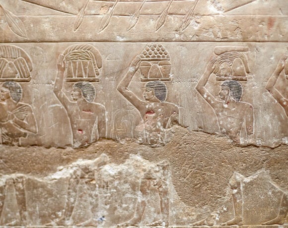 A procession of men carrying food offerings on their heads.